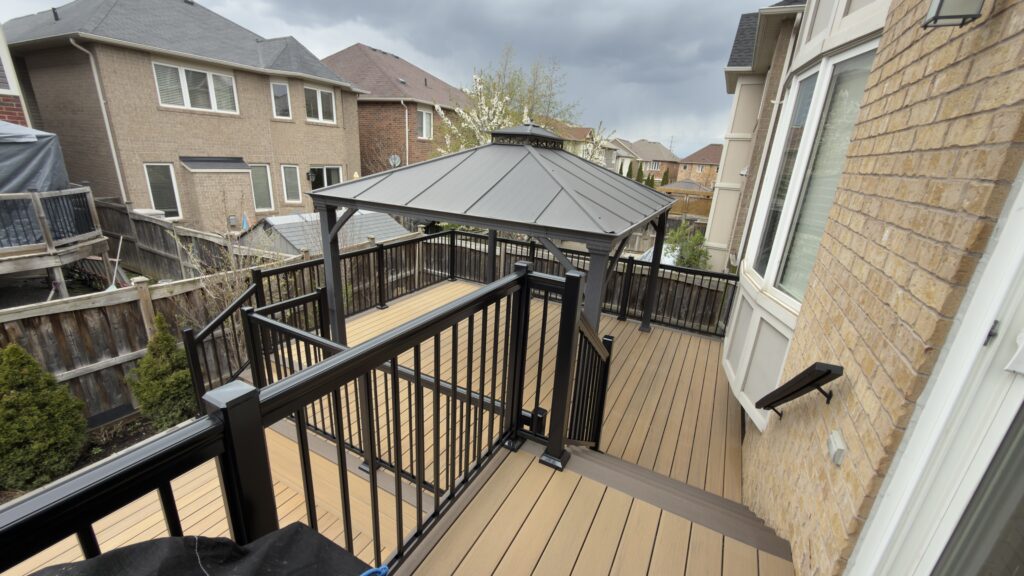 Elegant black aluminum railings installed on large backyard entertainment deck with stairs